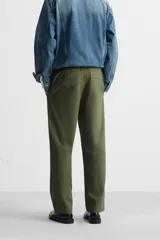 Pantalón chino color verde militar, de corte recto, con bolsillos laterales y traseros de vivo. Cierre frontal con cremallera y botón.