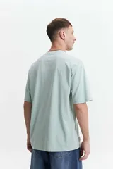 Remera de manga corta color marrón claro, de corte amplio y cuello redondo.