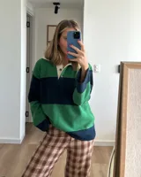 Sweater verde y azul marino con cuello polo blanco y cierre parcial con botones.