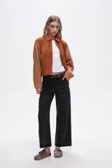 Chaqueta corta color marrón con detalles en color camel, de gamuza sintética, con cuello camisero, cierre frontal con cremallera y apliques de tachas plateadas.