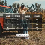 Campera de peluche negra con mangas largas color crema, cuello alto y cierre frontal. Presenta un parche con texto en el pecho.