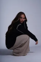 Cárdigan color beige con botones negros, escote en V y detalles de costuras bordadas en negro.