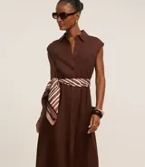 Vestido chemise de lino color negro, con cuello camisero, sin mangas y cierre frontal con botones. Incluye cinturón de tela estampado.