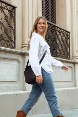 Bandolera negra de cuero con correa ajustable, cierre superior y bolsillo externo con cierre. Incluye bolsillo interno y logo de la marca grabado en el frente.