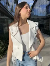 Chaleco blanco de cuero sintético con cierre cruzado, cuello solapa y cinturón con hebilla.