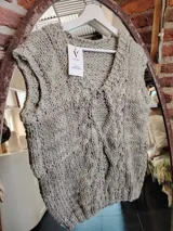 Chaleco tejido a mano color gris claro, con cuello en V y diseño trenzado.