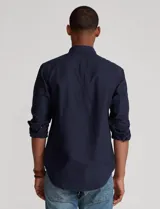 Camisa blanca de corte clásico, confeccionada en tejido oxford de algodón. Presenta cuello button-down, manga larga con puños abotonados y logo bordado en el pecho.