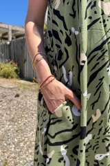 Vestido largo verde con estampado abstracto en blanco y negro, de fibrana, con breteles finos y volado en el ruedo.