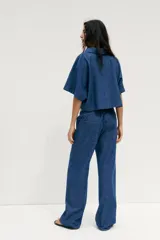 Pantalón de jean azul con cintura elástica ajustable con cordones, tiro medio y bolsillos de parche en la parte trasera.