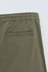 Pantalón cargo negro de corte slim fit, confeccionado en tejido de algodón con cintura elástica ajustable con cordón. Cuenta con bolsillos frontales, traseros y bolsillos tipo parche con solapa en los laterales.