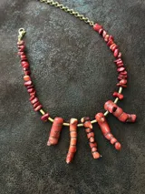 Collar corto con cuentas de coral rojo, bastones de bronce y cadena de acero quirúrgico con cierre de gancho ajustable.
