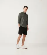 Camisa verde militar de manga larga en sarga de algodón, con cuello clásico, cierre frontal abotonado y dos bolsillos con solapa abotonada en el pecho.