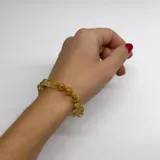 Pulsera elástica con cuentas de citrino de 6 mm de diámetro y separadores de hilo beige. Terminaciones en acero hipoalergénico con baño dorado.