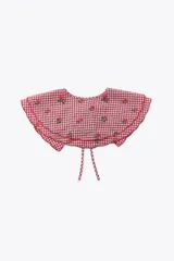Cuello desmontable con estampado de cuadros vichy rojos y blancos, detalle de flores bordadas y volados en el borde. Se ata al frente con lazos del mismo tejido.