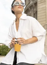 Camisa oversize blanca confeccionada en lino, con cuello camisero clásico, cartera con botones de nácar a la vista y puños con tablitas.