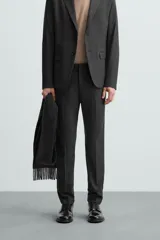 Pantalón de vestir gris oscuro, corte slim fit, con bolsillos laterales y traseros de ojal. Cierre frontal con cremallera y botón.