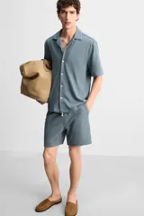 Bermuda azul de tejido con mezcla de algodón, corte relaxed fit, cintura elástica ajustable con cordón, bolsillos delanteros y detalle de bolsillo trasero de vivo.