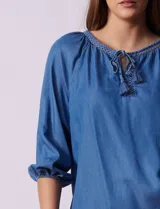 Blusa celeste de tencel con cuello a la base, escote en V con aplique de cordel y lazo de ajuste. Manga larga amplia con puño elastizado.