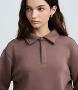 Saco femenino cerrado de algodón con felpa más sostenible, color beige. Presenta cuello polo con abotonado parcial, manga larga y bajo ajustado.