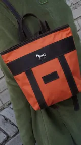 Mochila pequeña color borgoña con detalles en cuero marrón, asa de mano y correas ajustables.
