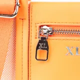 Cartera mini tipo tote bag bicolor, con cuerpo de tela color beige y solapa frontal de cuero sintético color naranja. Tiene doble asa de mano, correa larga regulable y herrajes plateados. Presenta un bolsillo externo con cierre y dos bolsillos internos, uno con cierre y otro abierto.