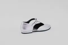 Zapato flat de cuero con estampado de vaca en blanco y negro, con tira delantera y hebilla lateral.