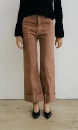 Pantalón jean color marrón con costuras a la vista, corte recto y dobladillo en el ruedo.