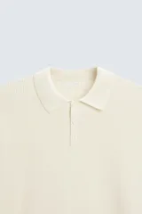 Polo marrón de corte relaxed fit, tejido en punto de algodón. Tiene cuello solapa con cierre frontal de botonadura, manga larga y acabados en rib.