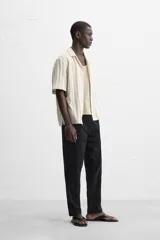 Camisa de manga corta con cuello bowling y corte relaxed fit, confeccionada en tejido con algodón y diseño a rayas verticales en tonos beige y blanco.