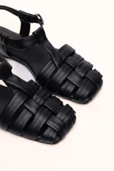 Sandalias franciscanas rojas de cuero con tiras entretejidas y hebilla lateral.