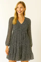 Vestido corto con estampado de flores blancas sobre fondo negro, escote en V y mangas largas abullonadas.
