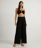 Pantalón wide leg negro de lino y viscosa, con cierre de botón y cremallera, trabillas y pliegues delanteros.