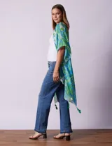 Kimono tejido con estampado abstracto en tonos verde, azul y blanco. Tiene mangas cortas amplias y terminación con borlas verdes en el ruedo.