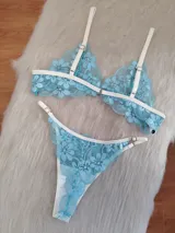 Conjunto de lencería confeccionado en encaje floral color aguamarina con detalles de elásticos en tono champagne. Incluye un corpiño de formato triangular sin aro y una bombacha tipo colaless con breteles regulables.