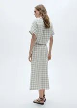 Falda midi de tiro alto con estampado de cuadros en tonos neutros. Presenta cierre lateral con cremallera, diseño evasé y costuras decorativas. Confeccionada en tejido ligero de algodón.