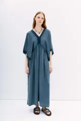 Vestido midi negro de calce amplio y mangas al codo. Tiene apliques de gasa en escote y mangas, y recortes con frunce en la cintura.