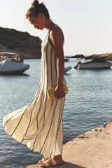 Bolso de mano tipo clutch color beige con apliques metálicos dorados. Incluye cadena metálica extraíble para usar como bandolera.