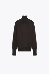 Jersey negro de punto liso con cuello alto, manga larga y detalle de botones dorados en los puños.