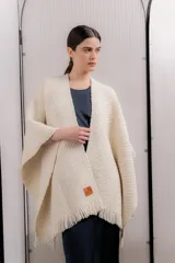 Ruana de tejido de punto color crema, con diseño abstracto bordado en la espalda en tonos celeste, rosa, naranja, azul y violeta.