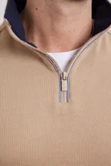Sweater color beige de tejido elastizado de algodón y poliéster, con medio cierre en el cuello, detalles de tela de algodón al tono y tirador de eco cuero.