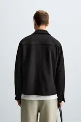 Sobrecamisa color beige de tejido efecto ante, corte regular fit, con cuello solapa, manga larga con puños abotonados, bolsillos de parche con solapa en el pecho y bolsillos de ojal en la cadera.