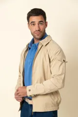Campera color beige con cierre frontal, cuello camisero, bolsillos laterales y elástico en la cintura. Detalle de bolsillo en la manga izquierda.