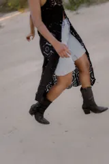 Bota texana de cuero color beige con punta marcada, caña media y flecos decorativos en el lateral externo.