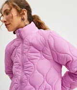 Campera femenina de poliamida color lila con textura capitoneada, cuello alto, cierre frontal con cremallera, bolsillos laterales con cremallera y puños ajustados.