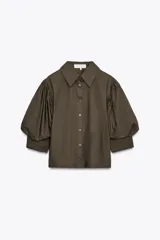 Camisa color verde oliva de popelina de algodón, con cuello solapa, manga corta abullonada y cierre frontal con botones.