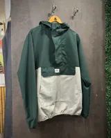 Rompevientos verde oscuro y gris con capucha, cierre frontal parcial y bolsillo tipo canguro.