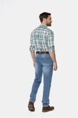 Pantalón de jean azul oscuro de corte recto y tiro medio. Incluye cinturón de cuero marrón y botas de gamuza marrón.