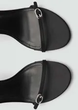 Sandalias negras de tacón fino, con tira delgada sobre los dedos y pulsera con hebilla al tobillo.