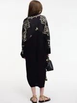 Vestido camisero negro con bordados dorados de motivos geométricos.