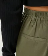 Pantalón jogger color verde militar, con cintura elástica ajustable con cinturón de hebilla plástica. Tiene bolsillos laterales tipo cargo con fuelle y puños elásticos.